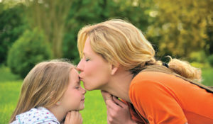 a woman kissing the forehead of a child